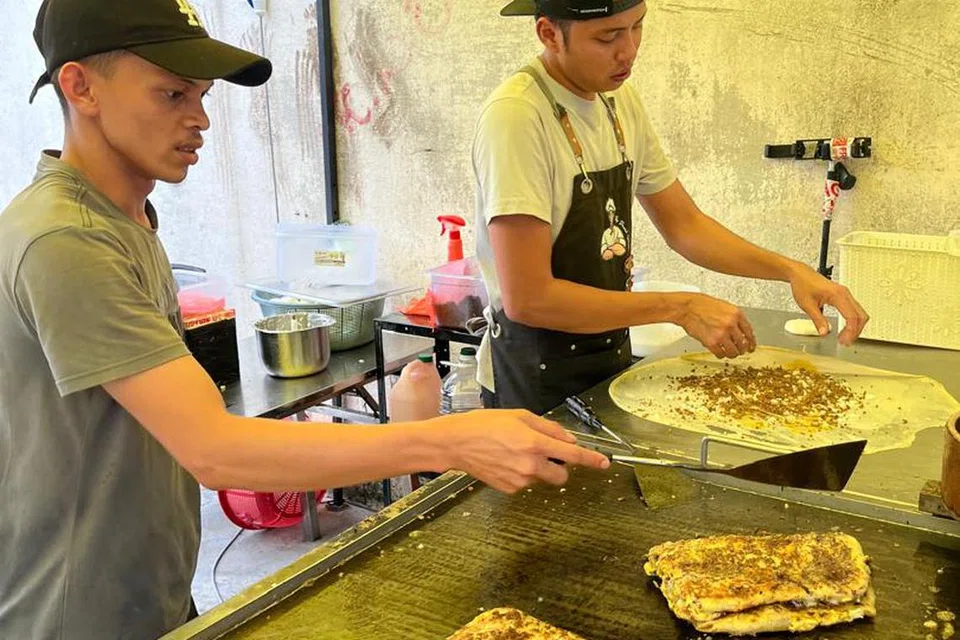 Encik Mohd Daniel Shukor, 34 tahun (kanan), gigih memenuhi permintaan pelanggan gerainya, ‘Murtabak Singapore Dari Rumah’ (MSDR), dan dibantu pekerjanya di kedai MSDR di Taman Melawati, Kuala Lumpur.