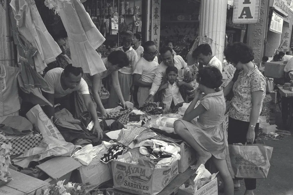 Sekumpulan pelanggan sibuk memilih pakaian di kedai yang mengadakan jualan istimewa sempena musim perayaan Hari Raya. Gambar ini dirakamkan pada 31 Januari 1965. 