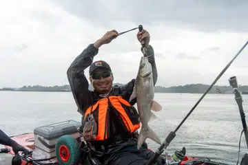 Wartawan, Muhd Hazman Abd Aziz, bergambar bersama ikan pertama yang ditangkapnya di pantai Changi. 