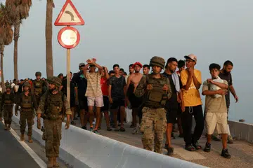 Anggota tentera mengiringi sekumpulan pendatang di Ceuta, Sepanyol, pada 1 Ogos 2026, selepas puluhan ribu orang menyeberang dari Maghribi ke wilayah Sepanyol itu melalui darat dan laut. Antara 3,000 dengan 5,000 pendatang dipercayai masih berada di Ceuta, termasuk lebih 1,000 kanak-kanak tanpa penjaga. Kumpulan bantuan memberi amaran bahawa sebahagian kanak-kanak terpaksa tidur di jalanan dan pantai, sekali gus mendedahkan mereka kepada risiko keganasan, pemerdagangan manusia dan eksploitasi.
