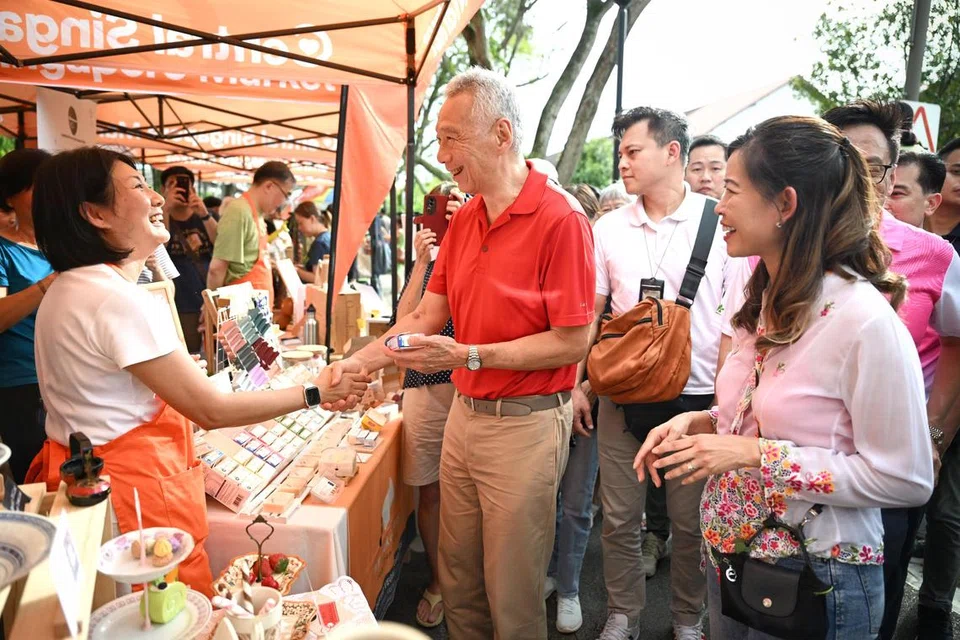 Menteri Kanan, Encik Lee Hsien Loong (tengah), dan Anggota Parlimen (AP) GRC Ang Mo Kio, Cik Ng Ling Ling (kanan), di Karnival Penduduk Seletar Hills yang diadakan di Taman Jalan Selaseh pada 23 Mac. 