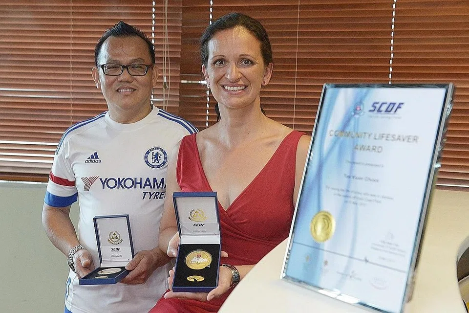 USAHA MENYELAMAT DIHARGAI: Encik Tan Kian Choon dan Cik Silvia Hajas menerima anugerah SCDF atas usaha mereka membantu menyelamatkan tiga kanak-kanak lelaki yang hampir lemas di Taman East Coast baru-baru ini. - Foto THE STRAITS TIMES