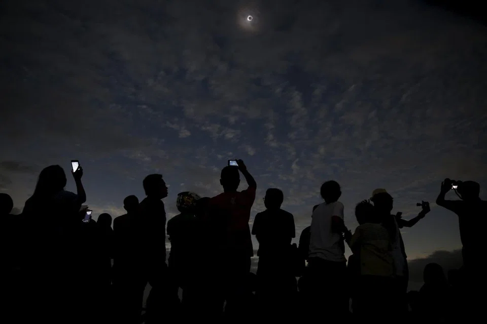 SUASANA GELAP GARA-GARA GERHANA PENUH: Orang ramai berebut-rebut mengambil gambar semasa gerhana matahari di pantai Ternate, Indonesia.
