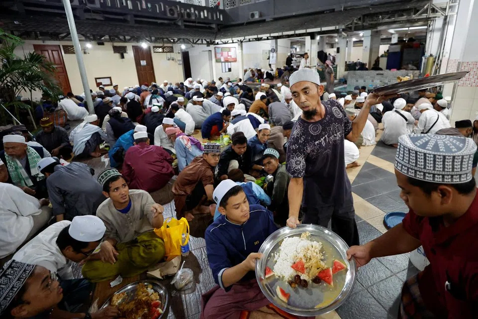 Jemaah Masjid Kebon Jeruk Jami yang terletak di Jakarta, Indonesia, berhimpun di halaman masjid untuk berbuka puasa pada 12 Mac. Beberapa anggota jemaah membantu mengagihkan hidangan kepada yang lain.