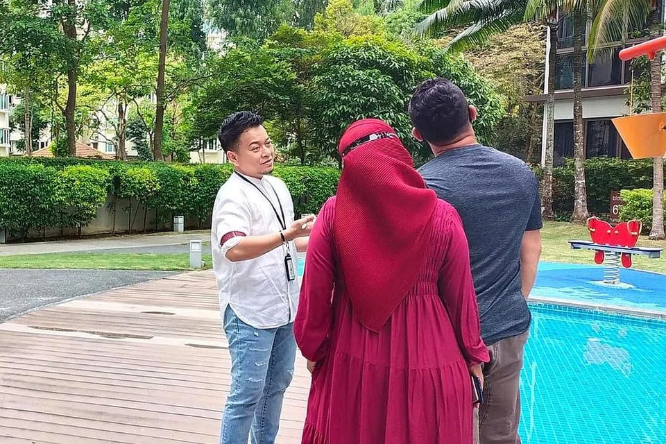 SEMENTARA MENANTI FLAT BTO: Cik Rina (bertudung) berserta suaminya Encik Dean mendapat penerangan daripada agen hartanah mereka, Encik Muhammad Syafiq Mohd Esa (kiri), mengenai kondominium yang mereka sewa. - Foto IHSAN MUHAMMAD SYAFIQ