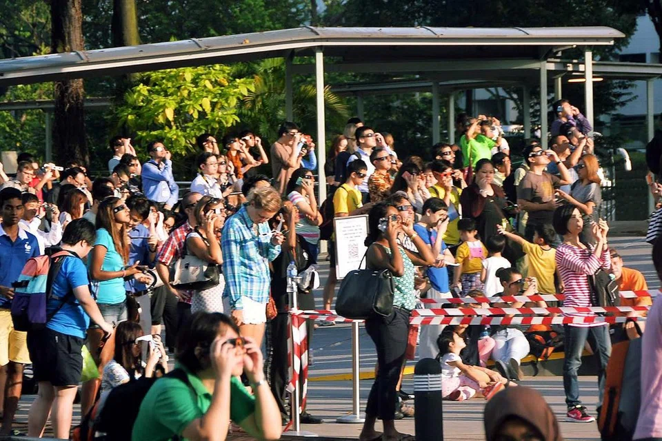 MENAKJUBKAN: Lebih 3,000 orang, yang terdiri daripada orang dewasa hingga kanak-kanak, membanjiri Pusat Sains Singapura kerana ingin menyaksikan fenomena gerhana matahari semalam. 