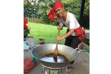 GAYA TRADISIONAL: Dalam satu tunjuk cara masak di Restoran Seri baru-baru ini, Encik Qamar menggunakan anglo untuk membuat wajik. Beliau mengacau gula secara konsisten sebelum memasukkan santan dan pulut. - Foto HANIM MOHD SALEH