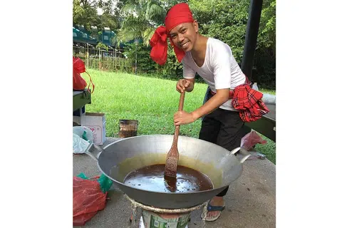 GAYA TRADISIONAL: Dalam satu tunjuk cara masak di Restoran Seri baru-baru ini, Encik Qamar menggunakan anglo untuk membuat wajik. Beliau mengacau gula secara konsisten sebelum memasukkan santan dan pulut. - Foto HANIM MOHD SALEH