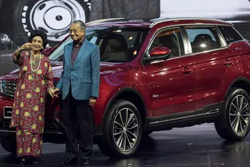 HARAP JADI KEBANGGAAN NEGARA: Dr Mahathir dan isteri Tun Dr Siti Hasmah bergambar di hadapan kereta jenis SUV, X70, yang dihasilkan menyusuli kerja sama Proton dan syarikat automotif dari China, Geely. - Foto EPA-EFE