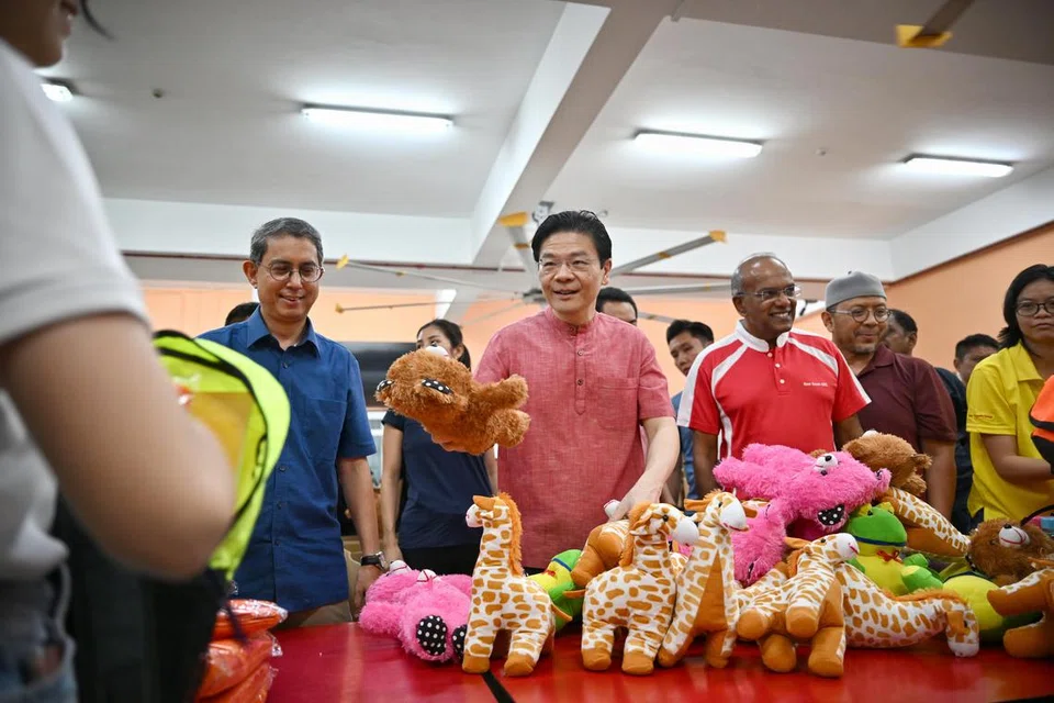 Perdana Menteri, Encik Lawrence Wong (tengah), bersama Menteri Ehwal Dalam Negeri merangkap Undang-Undang, Encik K. Shanmugam (tiga dari kanan) dan Menteri Negara (Ehwal Dalam Negeri merangkap Pembangunan Negara), Profesor Madya Dr Muhammad Faishal Ibrahim (kiri), turut hadir bagi membantu sukarelawan membungkus ‘Kidz Care Pack’ yang akan diberikan kepada kanak-kanak di Gaza.