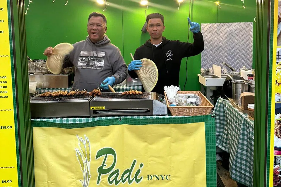 LEBAR SAYAP: (Dari kiri) Encik Hashim Ali dan anaknya, Mohamad Taufiq Hashim Ali, menyiapkan juadah semasa berniaga di gerai Padi D’NYC di Festival Bryant Park Winter Village, Manhattan, yang berlangsung dari 27 Oktober hingga 2 Januari 2024.