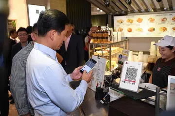 MUDAH DAN PANTAS: Encik Ong Ye Kung, Menteri Pendidikan dan anggota lembaga pengarah MAS, menggunakan kod QR, SGQR, untuk membuat pembayaran bagi kopi yang dibeli di Toast Box yang terletak bersebelahan Hotel Amara semalam. - Foto BH oleh KHALID BABA