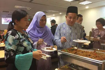 BERAYA BERSAMA: Encik Amrin bersama bekas pesakit barah buah dada, Cik Kamsiah Jupri (bertudung ungu) dan pekerja perubatan sosial, Cik Ernalisah Mohd Subhi (paling kiri) menjamu selera di perjumpaan Hari Raya di NCCS pada 30 Jun 2018.