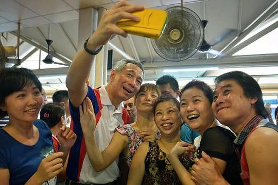 BERGAMBAR DENGAN PM: PM Lee mengambil 'we-fie' bersama beberapa penjaja di sebuah kedai kopi berdekatan pasar dan pusat makanan BlK 409 di Ang Mo Kio semalam. - Foto THE STRAITS TIMES