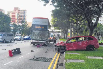 KEMALANGAN TERUK: Sebuah kereta Honda merah yang dipandu dengan begitu laju telah melanggar pemisah jalan dan sebuah bas yang penuh dengan penumpang. Kemalangan tersebut berlaku pagi semalam di Eunos Link. Tiada siapa yang cedera. - Foto THE STRAITS TIMES