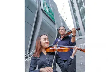 MUZIK KLASIK DEKAT DI HATI: Cik Nur Raeesah Abdul Malik (kiri) dan Cik Humaira Jasni menganggotai Kelab Ensembel Alat Tali Institusi Pengurusan Singapura (SIM) kerana ingin menggilap seberapa banyak ilmu menggesek biola dan membuat persembahan di khalayak ramai. Saksikan mereka beraksi dalam konsert klasik 'SIMphony 9 - Viaggio' di Teater Seni Pementasan SIM Sabtu ini. - Foto SIM