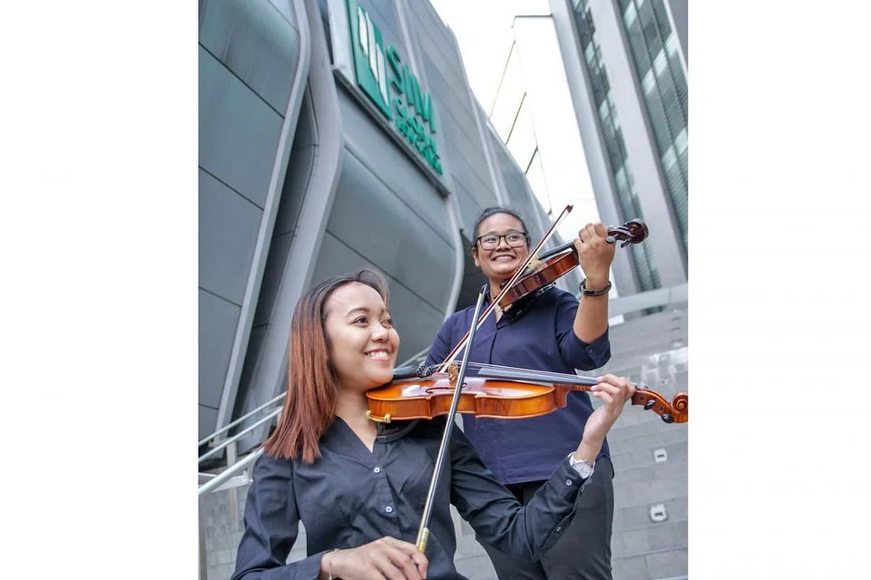 MUZIK KLASIK DEKAT DI HATI: Cik Nur Raeesah Abdul Malik (kiri) dan Cik Humaira Jasni menganggotai Kelab Ensembel Alat Tali Institusi Pengurusan Singapura (SIM) kerana ingin menggilap seberapa banyak ilmu menggesek biola dan membuat persembahan di khalayak ramai. Saksikan mereka beraksi dalam konsert klasik 'SIMphony 9 - Viaggio' di Teater Seni Pementasan SIM Sabtu ini. - Foto SIM