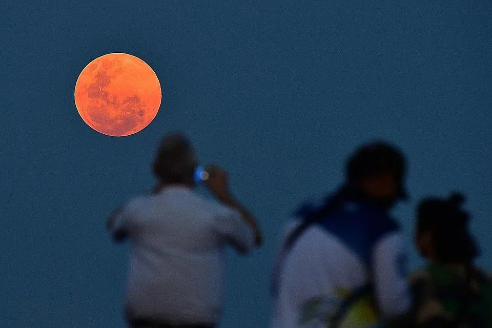 MALAM ISTIMEWA: Pengunjung di Jeti Bedok menyaksikan 'Supermoon' pada 19 Februari lalu, yang bertepatan dengan sambutan Chap Goh Meh, yang menandakan kemuncak dan hari terakhir sambutan Tahun Baru Cina. - Foto BH oleh LIM YAOHUI