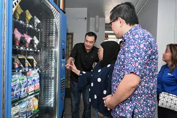 Cik Noorasikin Bahadrul Hisham (dua dari kiri), seorang penduduk kawasan Zhenghua, menggunakan mesin layan diri semasa pelancaran Projek Sama Sama @ North West pada 6 Julai yang dihadiri Mayor Majlis Pembangunan Masyarakat (CDC) North West, Encik Alex Yam (tiga dari kiri).