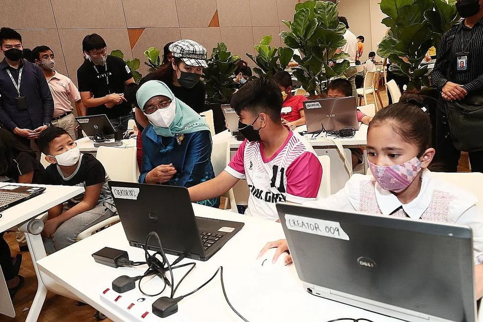 BINA ALAM MAYA IMPIAN MEREKA: Presiden Halimah Yacob (tiga dari kanan) berinteraksi dengan Muhammad Aqil, 12 tahun dan Nur Darliaarissa, 10 tahun, yang berpeluang mempelajari pengekodan untuk membina alam dalam ruang realiti maya impian mereka. - Foto BM oleh KELVIN CHNG