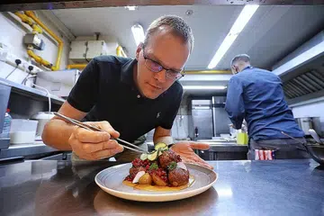 KAFE MEMPERBAIKI HIDANGAN: Pemilik bersama Fika, Encik Joakim Hesham Smidhagen (kiri), menghidangkan sajian 'Swedish meatballs' di dapur restoran. - Foto BH oleh KEVIN LIM