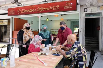 BUKA KEDAI MAKAN: Antara yang mengendalikan Hamidah's Kitchen ialah adik-beradik (dari kiri, berdiri) - Cik Maimunah Abdul Majid, Cik Fadilah Abdul Majid dan Encik Badruzzaman Abdul Majid - melayani tetamu yang menjamu selera di kedai mereka yang terletak di Simpang Bedok. - Foto BH oleh KHALID BABA