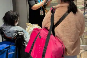 Seorang pekerja sedang membantu penumpang yang terperangkap antara jampatan pelepasan dengan pintu keluar ke ruang transit, setelah mendarat dari penerbangan Cathay Pacific. 