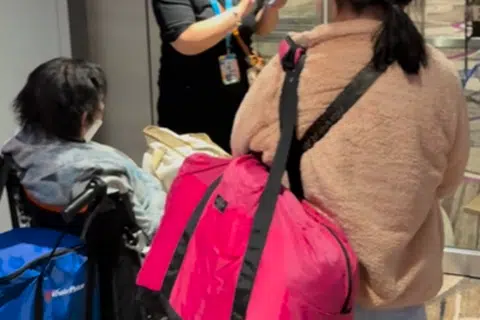 Seorang pekerja sedang membantu penumpang yang terperangkap antara jampatan pelepasan dengan pintu keluar ke ruang transit, setelah mendarat dari penerbangan Cathay Pacific. 