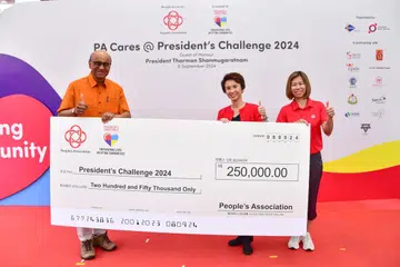 Presiden Tharman Shanmugaratnam (kiri) terima cek $250,000 daripada Cik Low Yen Ling (tengah), dan penolong ketua eksekutif Persatuan Rakyat, Cik Jeanie Tan.