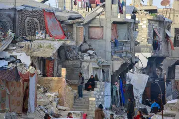 Penduduk Palestin duduk di tengah runtuhan bangunan yang musnah akibat serangan tentera Israel di Khan Yunis, selatan Jaluran Gaza, pada 27 Januari.