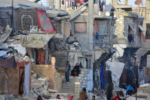 Penduduk Palestin duduk di tengah runtuhan bangunan yang musnah akibat serangan tentera Israel di Khan Yunis, selatan Jaluran Gaza, pada 27 Januari.