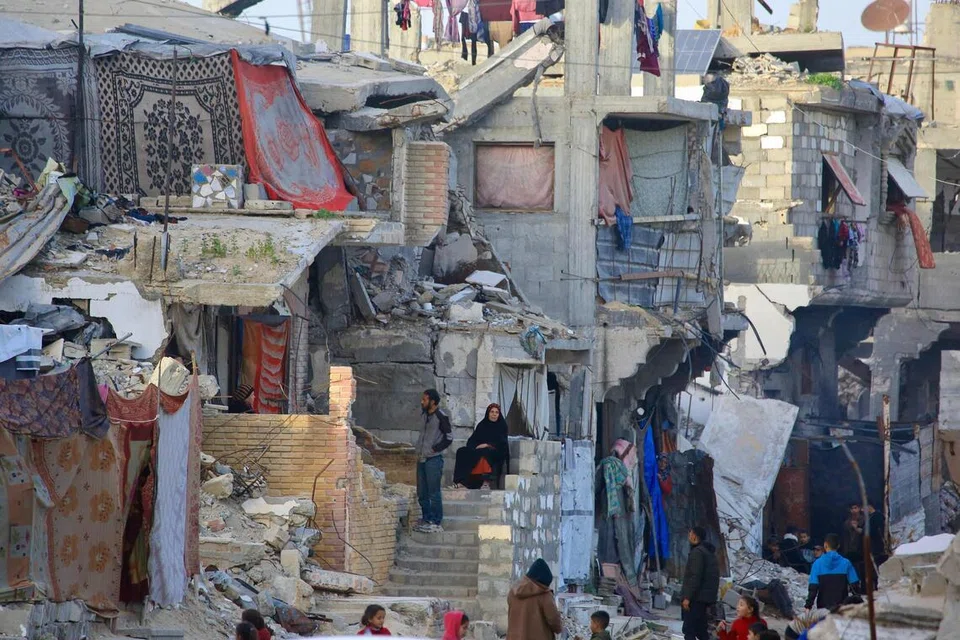 Penduduk Palestin duduk di tengah runtuhan bangunan yang musnah akibat serangan tentera Israel di Khan Yunis, selatan Jaluran Gaza, pada 27 Januari.