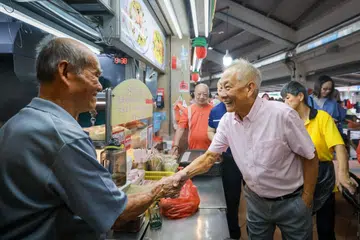 TEMU WARGA: Calon Pilihan Raya Presiden, Encik Ng Kok Song (kanan), berinteraksi dengan warga Singapura termasuk peniaga di Pasar Bulat di Tampines pada Ahad pagi.