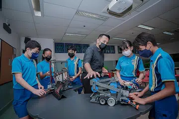 TINGKATKAN KEMAHIRAN: Encik Muhammad Reza Daud (tengah) berkata kemahiran yang dipelajari anak muridnya dalam robotik tidak hanya tertumpu kepada bagaimana mengendalikan robot tetapi juga aspek lain seperti Matematik, semangat berpasukan dan kepimpinan. Antara murid yang terlibat dalam kokurikular itu termasuk (dari kiri) Choong Weng Tat, Nur Sharlyz Mohammed Ilmifidri, Akshit Jaggi, Megan Chloe Sutiono dan Irfan Bazil Shahreen. - Foto BH oleh NUR DIYANA TAHA