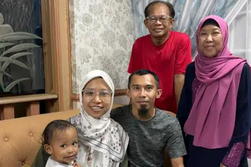 Cik Hasnah Masnod (kanan) akan menerima bantuan tunai $500 menerusi Bayaran Khas Kos Sara Hidup (COL) bermula 9 September. Turut menerima bantuan tunai itu ialah suaminya, Encik  Mawi Ismail (dua dari kanan). Bersama mereka ialah anaknya, Encik Muhammad Hafiz Mawi (tengah) dan isterinya, Cik Nur Imanina Aminordin (dua dari kiri) yang mendukung anak, Ijaz Hanzal.