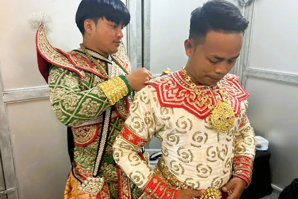 Tossasan Thongkhow (kiri) membantu Kiattisak Rungkhruea, menyarungkan pakaian watak Hanuman untuk tarian tradisi Thailand; ‘Khon’.