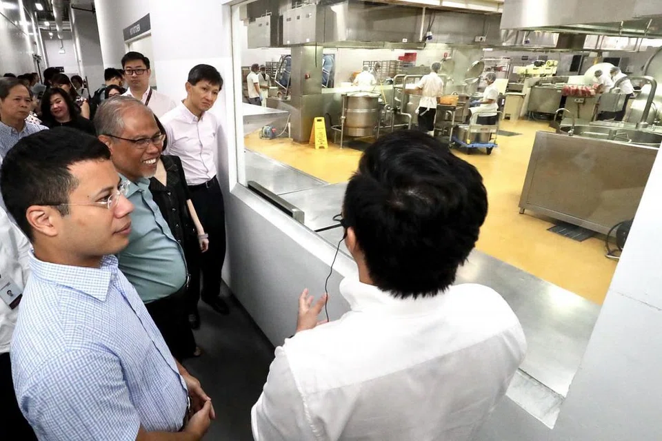 LAWATAN KE SYARIKAT MAKANAN: Menteri Sekitaran dan Sumber Air Masagos Zulkifli Masagos Mohamad (dua dari kiri) dan Menteri Kedua Pembangunan Negara Desmond Lee (kiri) mendengar penerangan yang disampaikan pegawai syarikat makanan The Soup Spoon Pte Ltd semasa mengadakan lawatan ke syarikat itu di Buroh Lane, Jurong West, semalam. - Foto LIANHE ZAOBAO