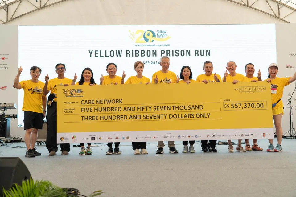 Menteri Kanan, Encik Lee Hsien Loong (enam dari kiri) dan Menteri Penerangan dan Pembangunan Digital merangkap Menteri Kedua Ehwal Dalam Negeri, Cik Josephine Teo (lima dari kanan) bergambar bersama cek dana yang dikumpulkan semasa Perlumbaan Penjara Reben Kuning 2024.