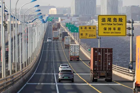  Lori yang membawa kontena penghantaran melintasi Jambatan Donghai untuk keluar dari Pelabuhan Yangshan di pinggir Shanghai, China, pada 7 Februari 2025