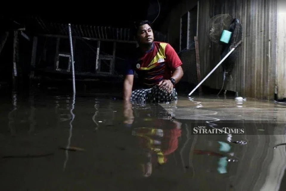 DITENGGELAMI AIR: Seorang penduduk Terengganu melihat keadaan rumahnya yang dimasuki dan ditenggelami air. - Foto NST
