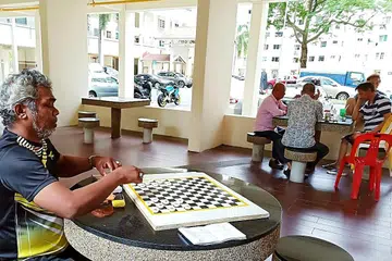  ISI MASA TERLUANG: Encik Samad (kiri) menunggu rakan-rakannya untuk bermain dam bersamanya di kolong Blok 146 Bedok Reservoir Road yang juga 'port' kaki dam. - Foto BH oleh SAINI SALLEH