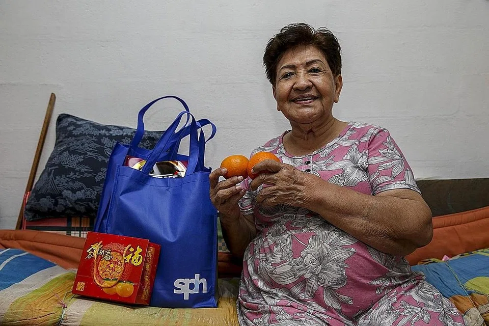 HABUAN PERAYAAN: Cik Goh Choo Lee bersama barangan yang diterima daripada kakitangan relawan Singapore Press Holdings kelmarin. Seramai 120 warga emas yang memerlukan di estet perumahan Toa Payoh menerima habuan sempena perayaan Tahun Baru Cina. - Foto BH oleh YONG LI XUAN