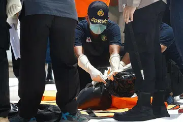 PENEMUAN HIBA: Seorang pegawai memeriksa beg jenazah (atas) mengandungi barangan atau cebisan mayat penumpang Sriwijaya Air. - Foto REUTERS