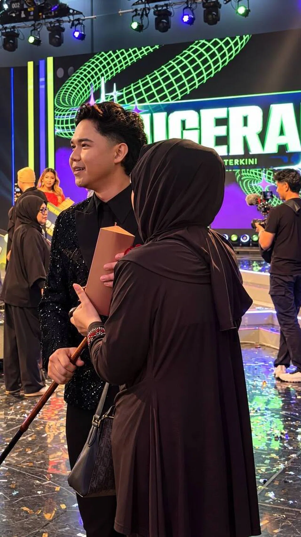 Izzan (kiri) bersama ibunya, Cik Juzana, yang hadir buat kali pertama untuk memberikan sokongan kepada anaknya pada malam kemuncak ‘Anugerah 2026’, yang diadakan pada 27 Oktober di Mediacorp Campus, meskipun berdepan masalah kesihatan akibat angin ahmar.