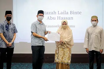 BERI PANDUAN DI DALAM DAN LUAR PENJARA: Dr Faishal menyampaikan surat pelantikan kepada Ustazah Laila (tengah), salah seorang daripada 80 asatizah yang telah menerima surat pelantikan yang melanjutkan khidmat mereka dalam program Fitrah. Turut bersama (dari kiri) Naib Pengarah Fitrah Mohd Farik Omar dan Mufti Dr Nazirudin. - Foto BH oleh GAVIN FOO