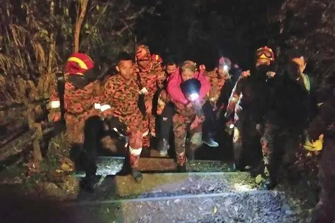 DIBANTU DENGAN SELAMAT: Seorang pendaki Gunung Kinabalu yang keletihan dibantu turun ke Timpohon Gate, salah satu daripada dua tempat mula dan berakhir pendakian gunung itu, pada awal pagi semalam selepas gempa bumi melanda. - Foto SIN CHEW DAILY