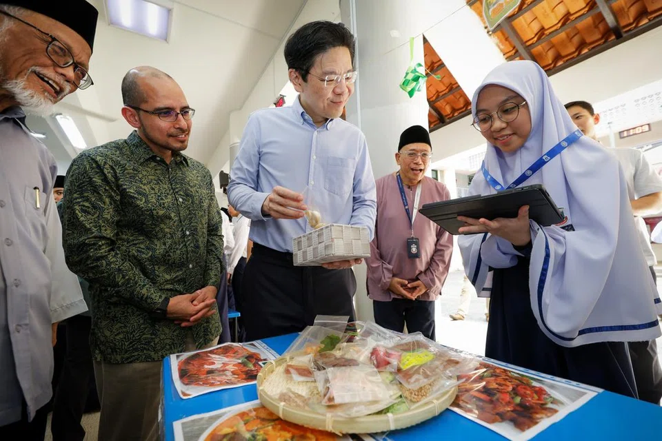 Perdana Menteri Lawrence Wong (tiga dari kiri) berinteraksi dengan pelajar Madrasah Aljunied Al-Islamiah dan belajar mengenai bahan masakan Rendang. Beliau diiringi (dari kiri) anggota Majlis Masyaikh Persatuan Ulama dan Guru-Guru Agama Islam Singapura (Pergas), Ustaz Pasuni Maulan dan mantan Anggota Parlimen Dilantik (NMP), Dr Syed Harun Alhabsyi.