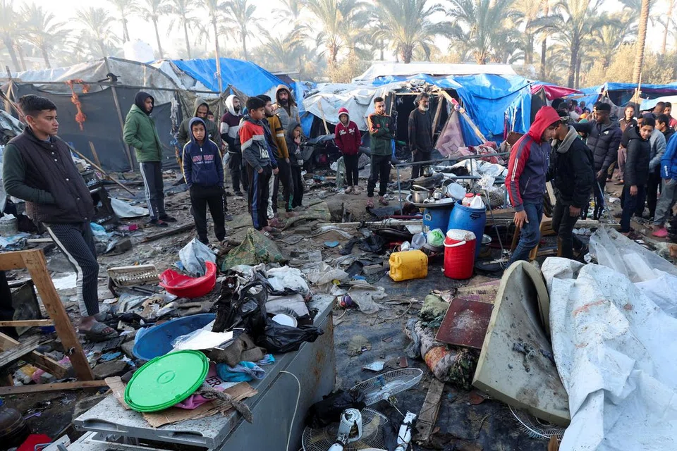 Rakyat Palestin meninjau kesan serangan Israel ke atas kem pelarian di Deir Al-Balah di tengah Jaluran Gaza pada 14 Januari. 