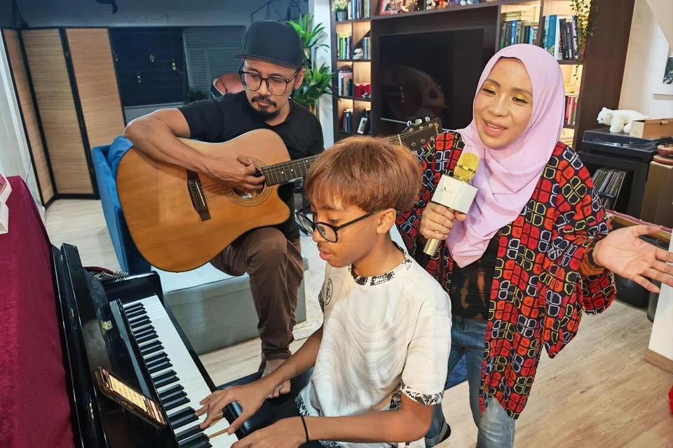 Penggiat seni dan budaya, Cik Asnida Daud (kanan), 53 tahun, telah menulis lagu Aok Diko yang diilhamkan daripada irama yang dimainkan anak beliau, Qurnia Jeffrey (tengah), 17 tahun, tujuh tahun yang lalu dan disusun suami beliau, Encik Jeffrey Zauhari (kiri), 52 tahun.