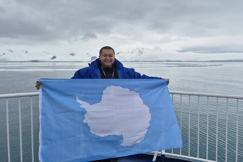 Penulis mengibarkan bendera Antartika dengan  latar belakang Kepulauan South Shetland.